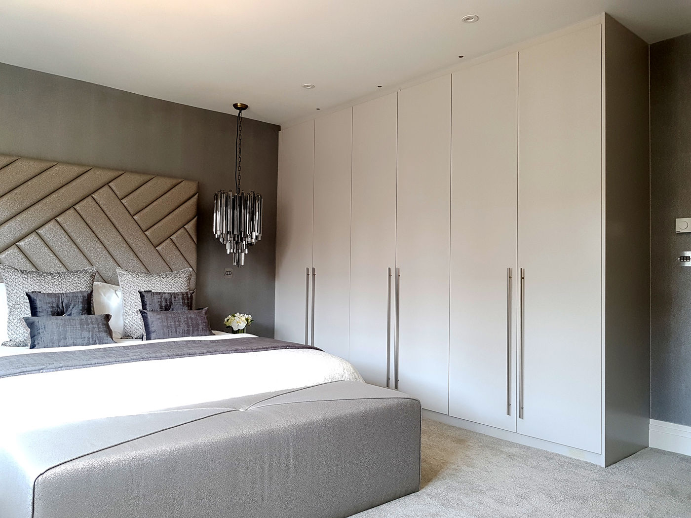 Bright view of completed light-grey floor-to-ceiling fitted wardrobes in a contemporary bedroom
