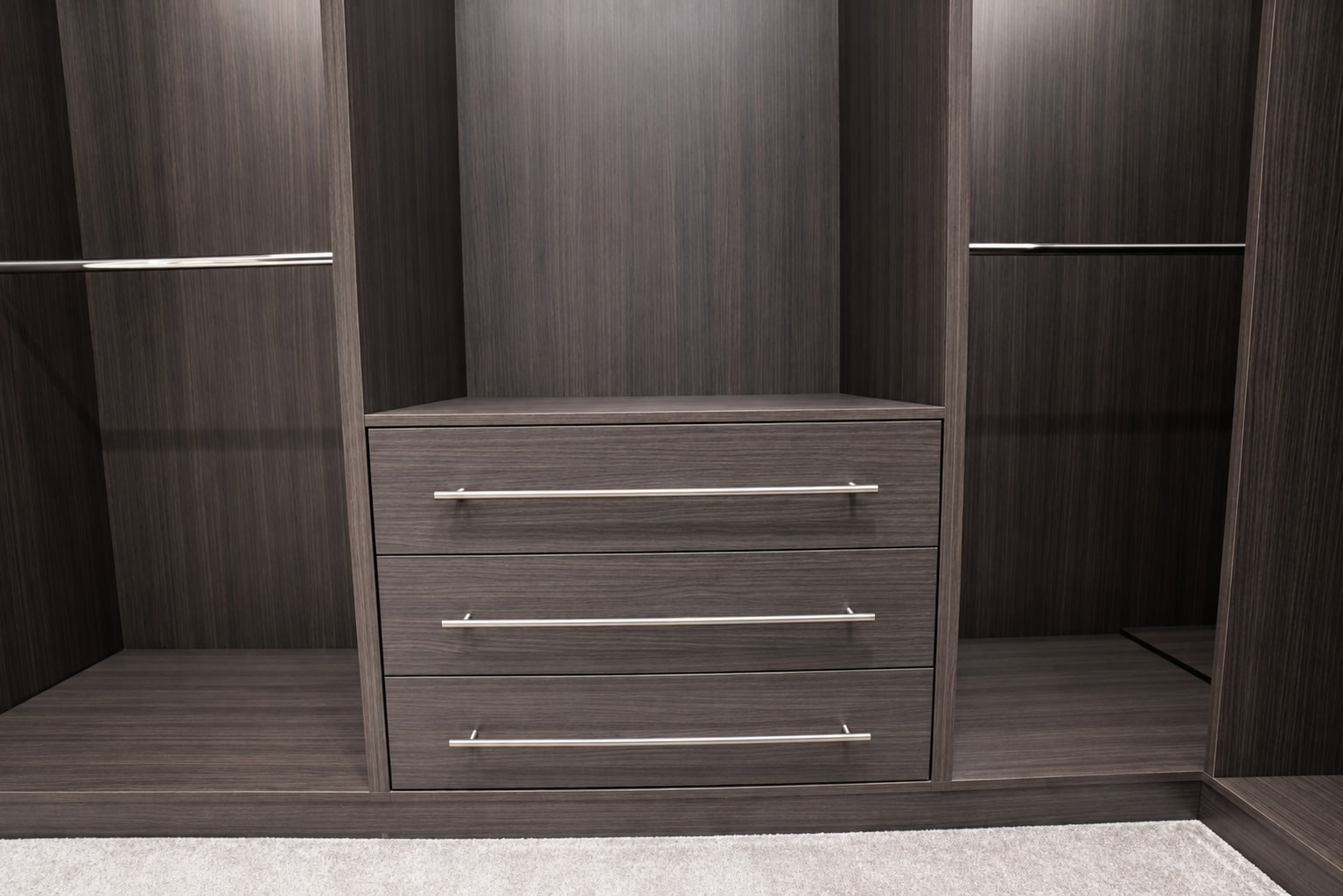 Dark woodgrain drawer unit within a walk-in wardrobe