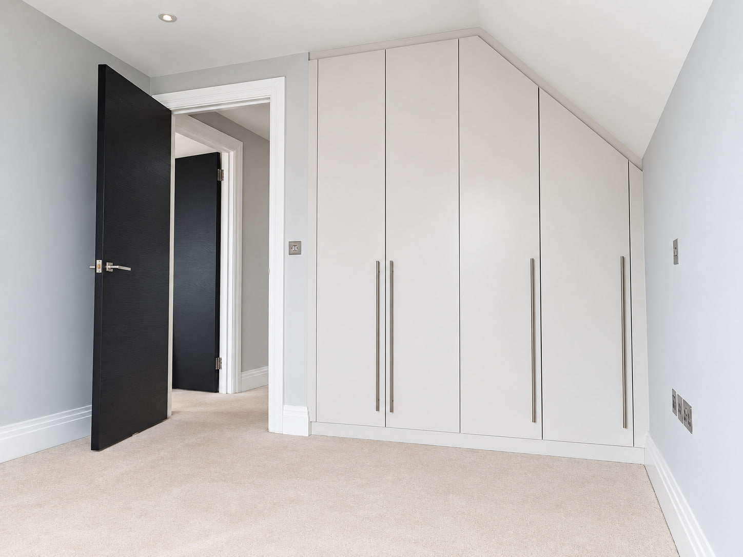 Wall-to-wall fitted wardrobe below a sloping ceiling