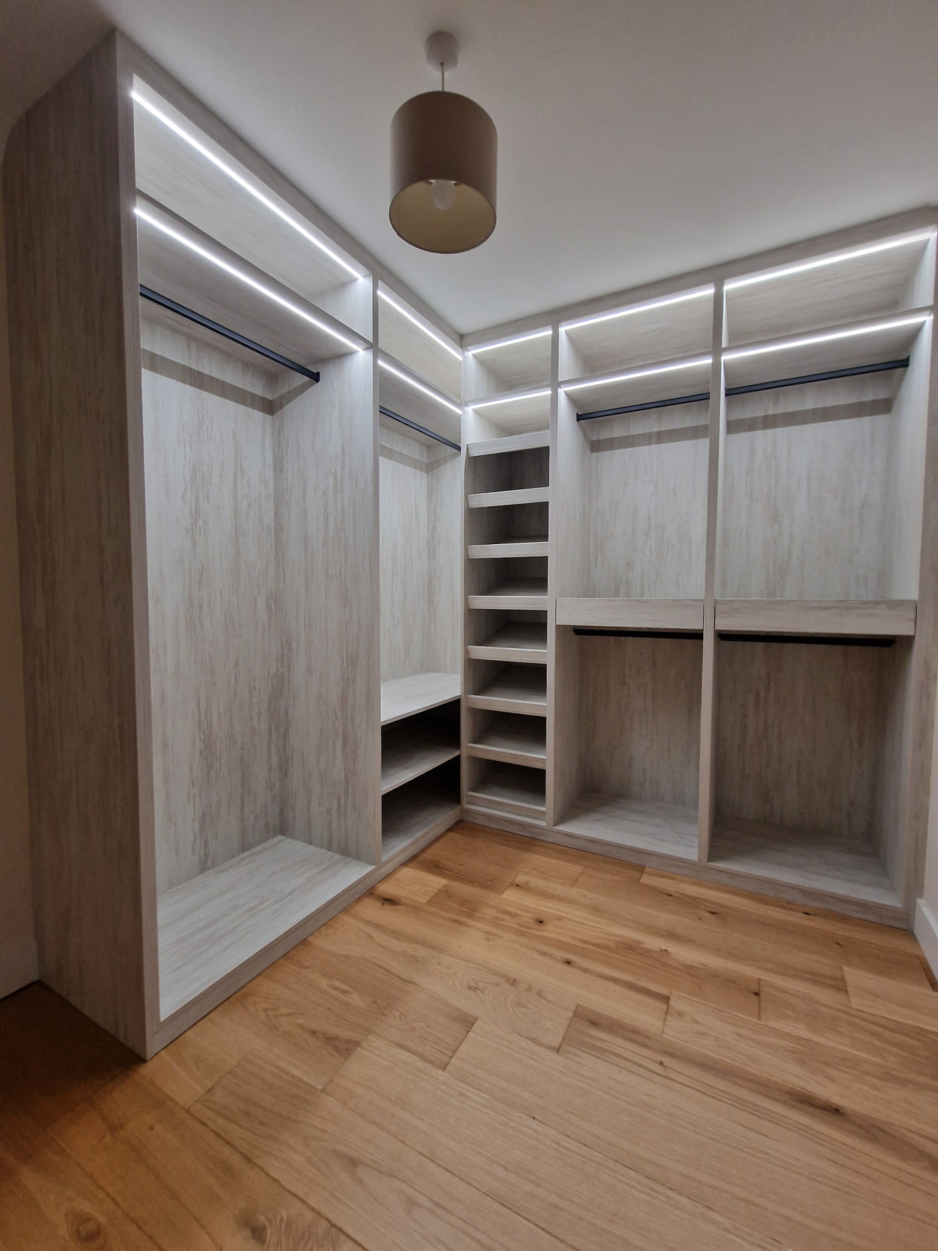 Wide-angle view of a completed light woodgrain walk-in wardrobe